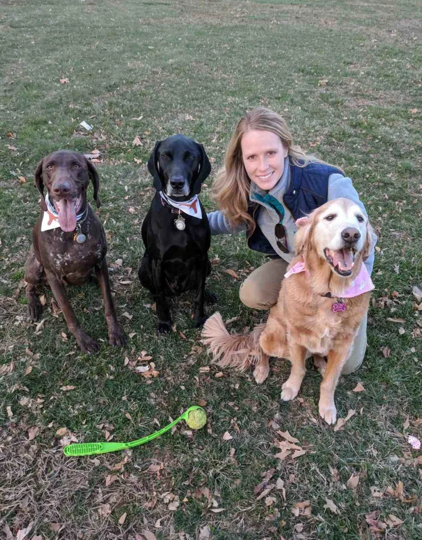 Dr. Amanda Wolff with three dogs on a grassy field